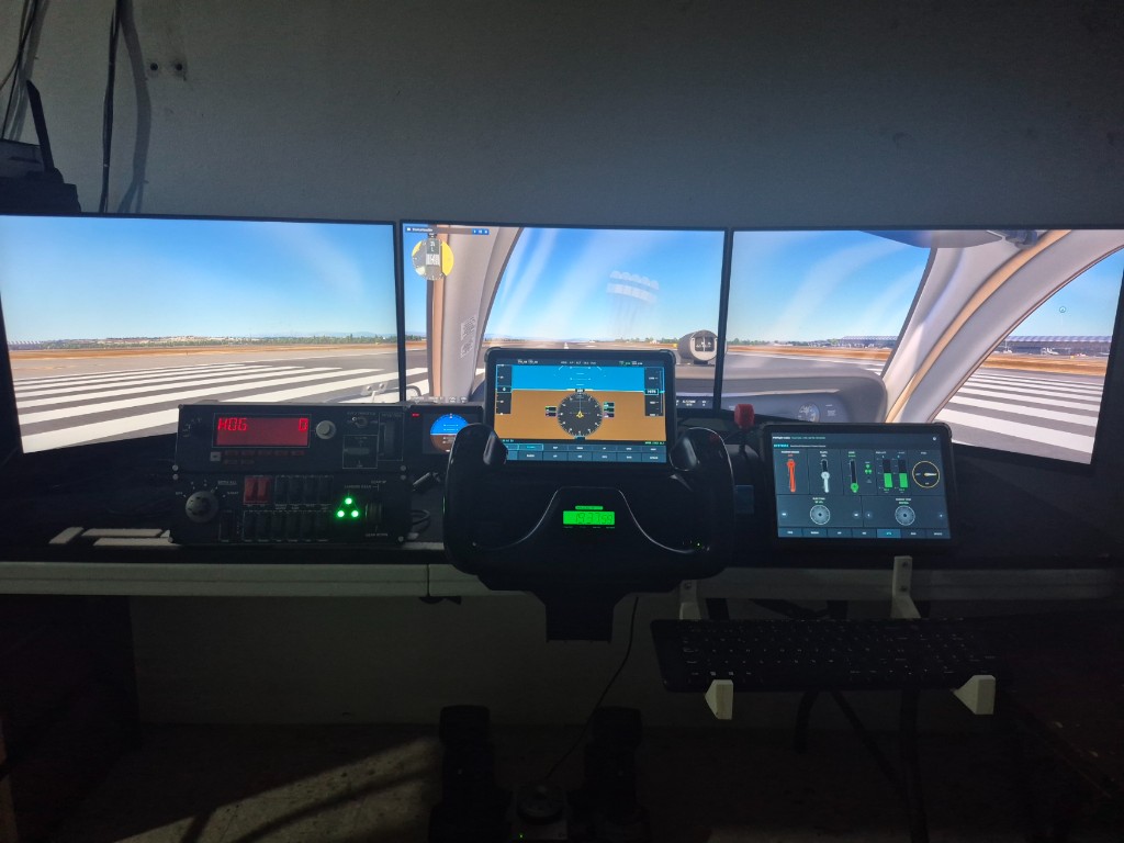 Home cockpit with triple monitors, yoke and two tablets running PGFlight Cabin G100